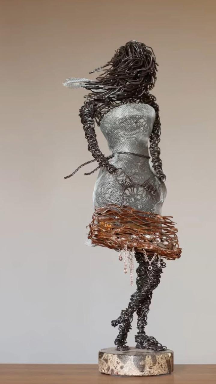 Sculpture of a woman made from wire and twigs on a neutral background